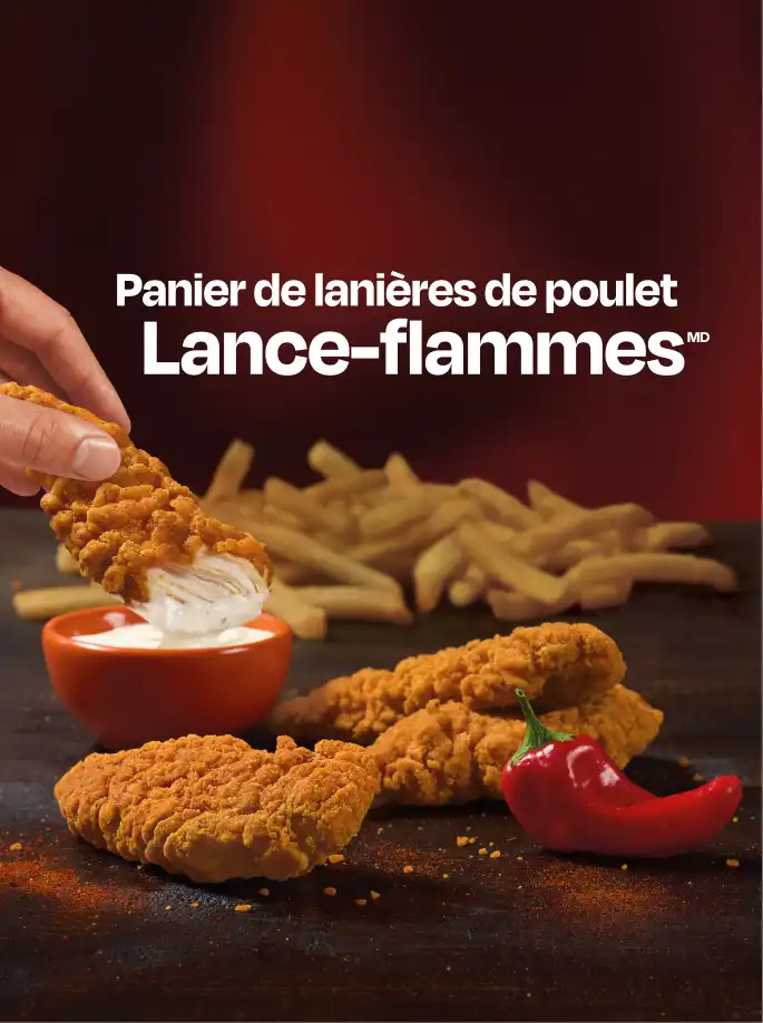 A hand dipping a Flamethrower chicken strip into dip