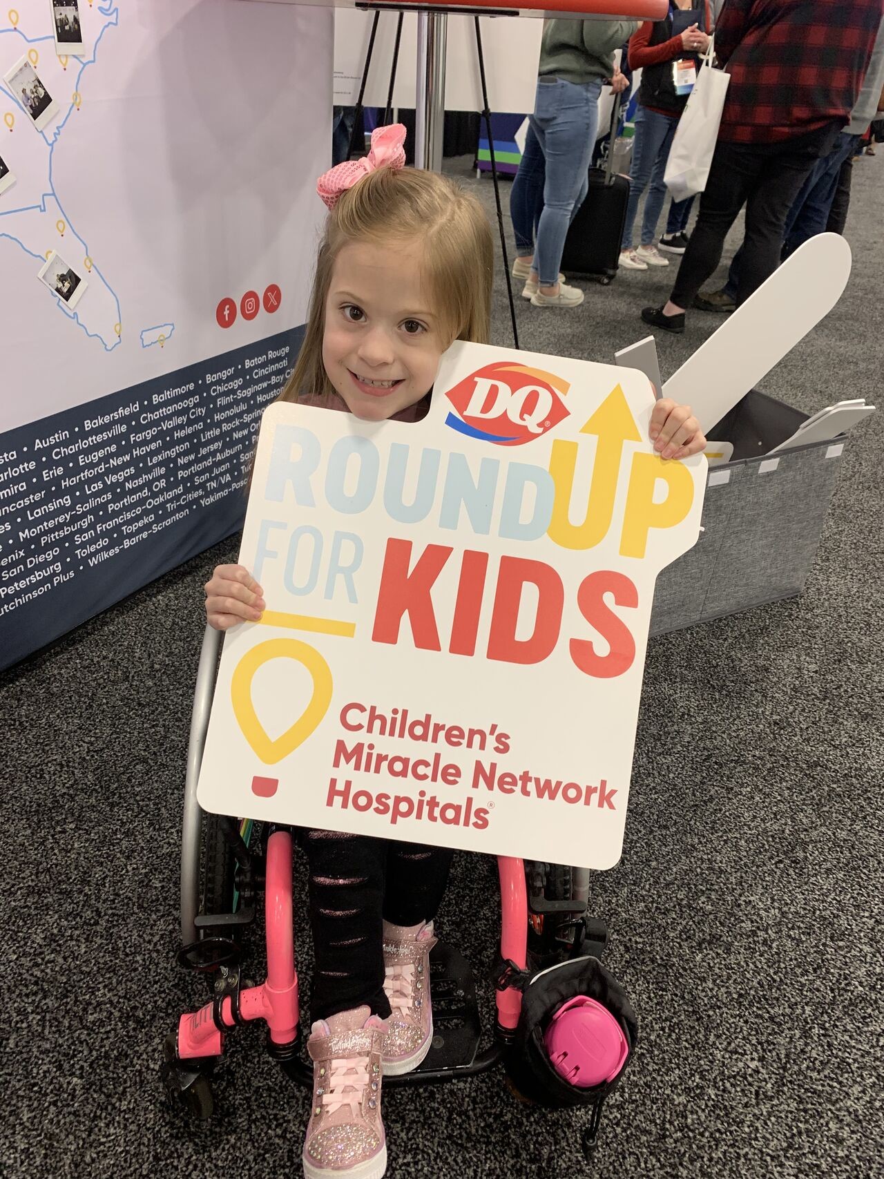 Child holding a Round up for Kids sign